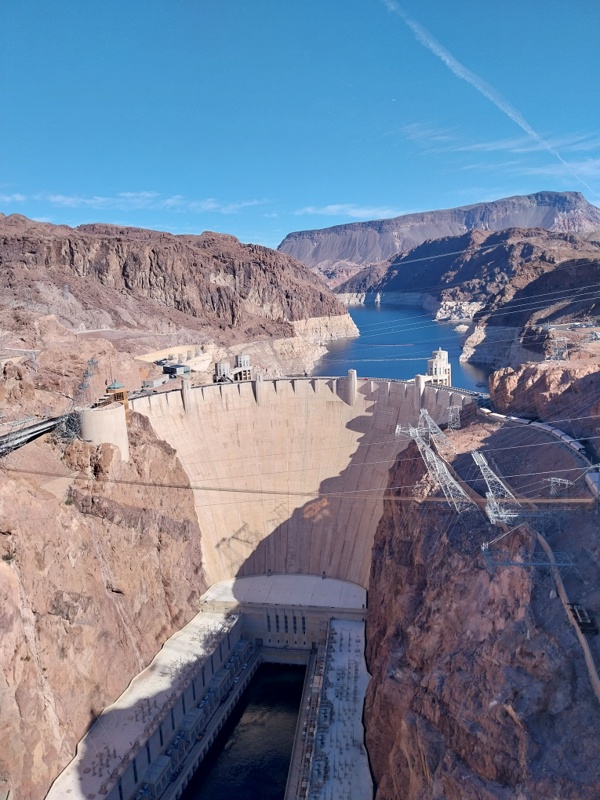 Staudamm mit schrägen Strommasten